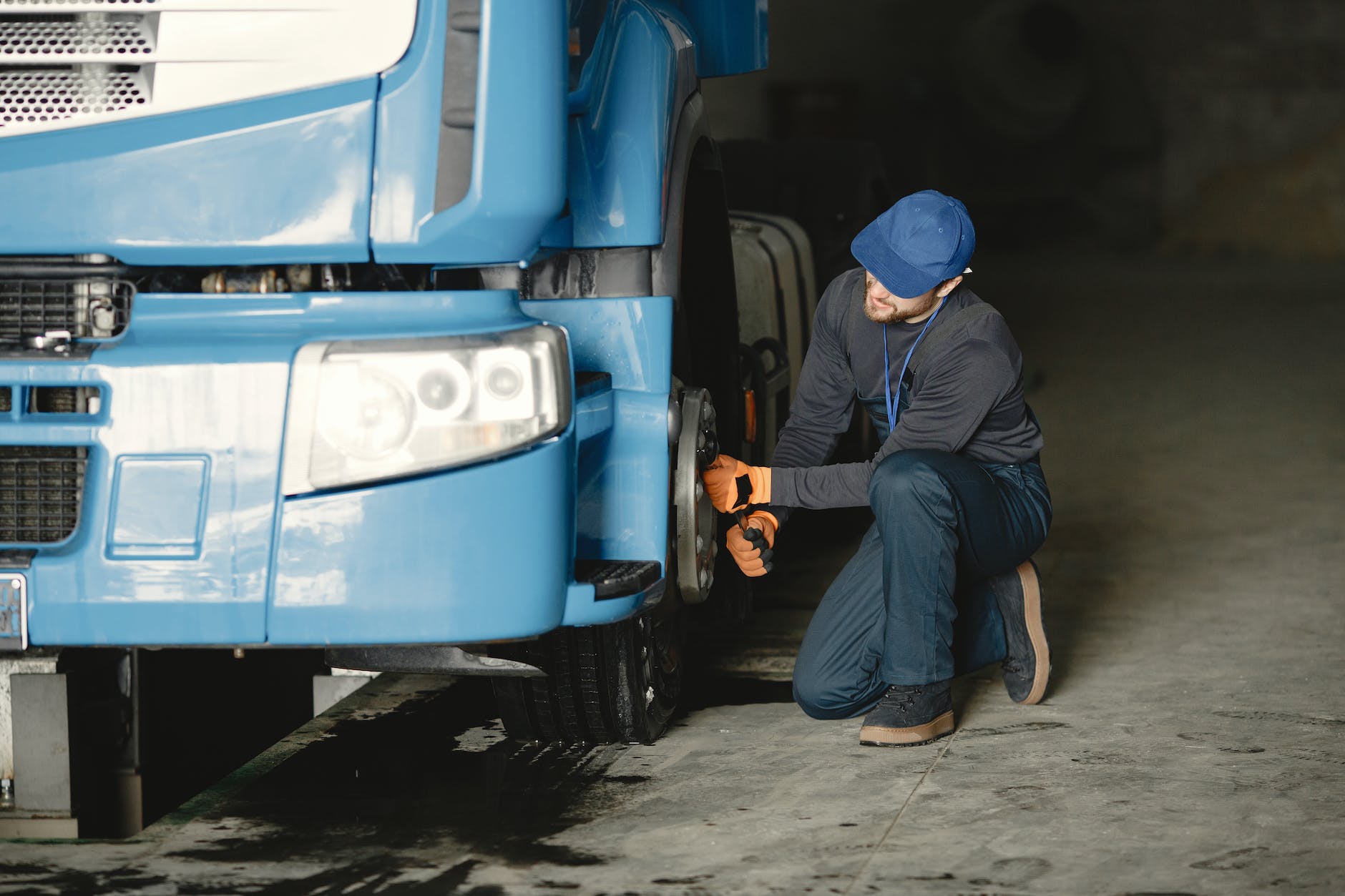 man in blue cap repairing blue truck s wheel