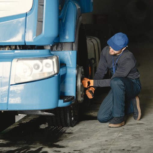 man in blue cap repairing blue truck s wheel