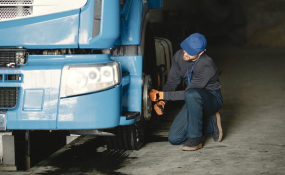 man in blue cap repairing blue truck s wheel